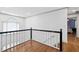 Bright hallway with gleaming hardwood floors and classic black and white banister detail at 3511 Stone Cliff Way, Woodstock, GA 30189
