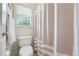 Bright bathroom with a classic toilet with beige and white stripped curtain next to a window at 1524 Guthrie Crossing Dr, Loganville, GA 30052