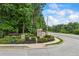Neighborhood sign with lush landscaping and a glimpse of the surrounding trees and street at 1524 Guthrie Crossing Dr, Loganville, GA 30052