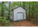 Exterior view of shed with roll up garage door, set amongst a heavily wooded lot at 1524 Guthrie Crossing Dr, Loganville, GA 30052