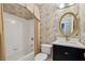 Charming bathroom with a tub/shower, elegant vanity, and decorative mirror and wallpaper at 770 Spalding Heights Dr, Atlanta, GA 30350
