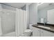 Well-lit bathroom with a shower-tub combo, white tile, and a vanity with dark countertops at 770 Spalding Heights Dr, Atlanta, GA 30350