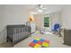 Bright Bedroom featuring a gray crib, plush carpet, and a ceiling fan with light at 770 Spalding Heights Dr, Atlanta, GA 30350