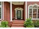 Inviting front entrance featuring a decorative glass door, red brick stairs, and lush landscaping with green plants at 770 Spalding Heights Dr, Atlanta, GA 30350