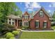Charming brick home with manicured lawn, mature trees, and inviting entryway with black shutters and basketball hoop at 770 Spalding Heights Dr, Atlanta, GA 30350