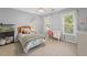 Cozy bedroom features a ceiling fan, neutral carpet, and two bright, airy windows with white trim at 390 Wilde Green Dr, Roswell, GA 30075