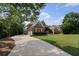 Long concrete driveway leading to a brick home surrounded by mature trees at 390 Wilde Green Dr, Roswell, GA 30075