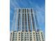 Modern high-rise condo building featuring floor-to-ceiling windows and sleek architectural design against a partly cloudy sky at 855 Peachtree Ne St # 1108, Atlanta, GA 30308