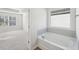 Relaxing bathroom with soaking tub, tiled surround, and view into the bedroom at 11857 Rizvan Pl, Covington, GA 30014