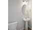 Close up of modern powder room featuring a pedestal sink, oval mirror, and modern light fixture at 11857 Rizvan Pl, Covington, GA 30014