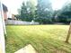 Grassy backyard with a wooden fence, lined by mature trees, and a home in the background at 350 Glynnshire Ct, Covington, GA 30016