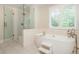 Elegant bathroom featuring a freestanding tub, a glass shower, and white marble tiling at 505 Junction Pt, Roswell, GA 30075