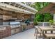 This outdoor kitchen has a built-in grill and mini-fridge with wooden accents and a dining area at 505 Junction Pt, Roswell, GA 30075