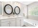 Bright bathroom with dual vanity sinks, a soaking tub, and a stylish decorative mirror at 7863 Kiverton Pl, Atlanta, GA 30350