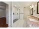 Bright bathroom featuring double vanity with granite counters and walk-in shower with marble surround and glass doors at 4984 Wickford Way, Atlanta, GA 30338