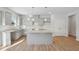 A kitchen featuring gray cabinets, stainless steel sink, island, granite counters, with wood-look floors at 11847 Rizvan Pl, Covington, GA 30014