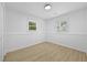 Bright bedroom featuring wood-look flooring, two windows, and neutral wall color at 400 Hunt River Way, Suwanee, GA 30024