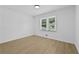 Empty bedroom with a window has wood grain floors and white walls at 400 Hunt River Way, Suwanee, GA 30024