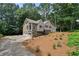 Two-story tan house with stone foundation and a three-car garage on a wooded lot at 400 Hunt River Way, Suwanee, GA 30024