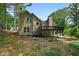 Back exterior view of a tan home featuring a wood deck and a wooded backyard at 400 Hunt River Way, Suwanee, GA 30024