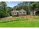 Front exterior view of a tan home featuring black shutters, a stone facade and a green lawn at 400 Hunt River Way, Suwanee, GA 30024
