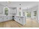 Bright kitchen features white cabinets, stainless steel appliances, an island, quartz countertops, and wood grain floors at 400 Hunt River Way, Suwanee, GA 30024