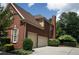 Brick house with a driveway and garage, surrounded by trees and shrubs at 200 Long Needle Ct, Sugar Hill, GA 30518