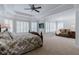 Large main bedroom features a sitting area, tray ceiling, fan, and many windows with plantation shutters at 200 Long Needle Ct, Sugar Hill, GA 30518