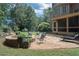 Stone patio with a fire pit and seating, surrounded by lush landscaping and a screened porch at 200 Long Needle Ct, Sugar Hill, GA 30518