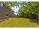 Large green backyard with two-story home, mulch rings around the trees, and a wooden fence at 3876 Thackary Dr, Powder Springs, GA 30127