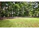 Well-maintained backyard with a green lawn, mature trees, and a classic wooden fence at 5040 Puritan Dr, Sugar Hill, GA 30518