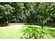 Lush green backyard with a wooden fence surrounding the perimeter and mature trees at 5040 Puritan Dr, Sugar Hill, GA 30518