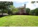 Exterior view of the home showcasing a well-kept lawn, deck, and mature trees at 5040 Puritan Dr, Sugar Hill, GA 30518