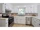Kitchen with stainless steel appliances, sleek backsplash, and abundant cabinet space at 5040 Puritan Dr, Sugar Hill, GA 30518