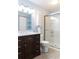 Bathroom with dark wood vanity, toilet, and enclosed glass shower at 6695 Grove Meadows Ln, Cumming, GA 30028