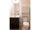 Well-lit bathroom with dark wood vanity and a built-in storage over the toilet at 6695 Grove Meadows Ln, Cumming, GA 30028