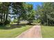 Home featuring a long driveway surrounded by mature trees and a lush green lawn at 28 Fawn Ct, Sharpsburg, GA 30277