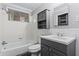 Well-lit bathroom with a shower-tub combination, vanity sink, and a storage cabinet above toilet at 4090 Tara Dr, Forest Park, GA 30297
