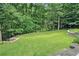 A spacious backyard with a manicured lawn and retaining wall is lined with trees at 1620 Stonecliff Dr, Decatur, GA 30033