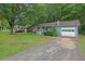 View of a light blue home with a well-kept lawn and an attached garage and mature trees at 5012 Galbraith Cir, Stone Mountain, GA 30088