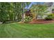 Spacious backyard featuring lush green grass, mature trees, and a charming landscaped garden at 2214 Trilleck Nw Dr, Kennesaw, GA 30152
