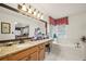 Bright bathroom featuring a granite countertop vanity, soaking tub, and large mirror reflecting the adjoining bedroom at 2214 Trilleck Nw Dr, Kennesaw, GA 30152
