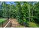 Secluded backyard with a wall, black metal fence, mature trees, and sloping landscape at 313 Anderwood Rdg, Marietta, GA 30064