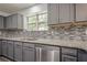 Renovated kitchen showcasing granite counters, mosaic backsplash, gray cabinetry, and stainless steel appliances at 4959 Abbotts Glen, Acworth, GA 30101