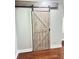 Bedroom featuring a stylish sliding barn door and a modern, hardwood floor design at 540 Langley Creek Dr, Loganville, GA 30052