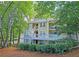 Two-story condo with a light yellow exterior, white railings, and surrounded by mature trees at 1202 Countryside Pl, Smyrna, GA 30080