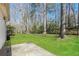 Expansive backyard with lush green grass, mature trees, and a concrete patio at 4100 Summer Wood Dr, Snellville, GA 30039