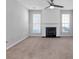 Open living room with neutral carpeting, a ceiling fan, and an elegant fireplace feature at 800 Tradd Ct, Stone Mountain, GA 30087