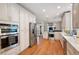 Modern kitchen featuring white cabinetry, stainless steel appliances, and hardwood flooring at 220 Mars Hill Rd, Powder Springs, GA 30127