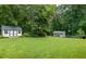 Large backyard with outbuildings on manicured lawn surrounded by mature trees at 555 Valley Hall Dr, Atlanta, GA 30350